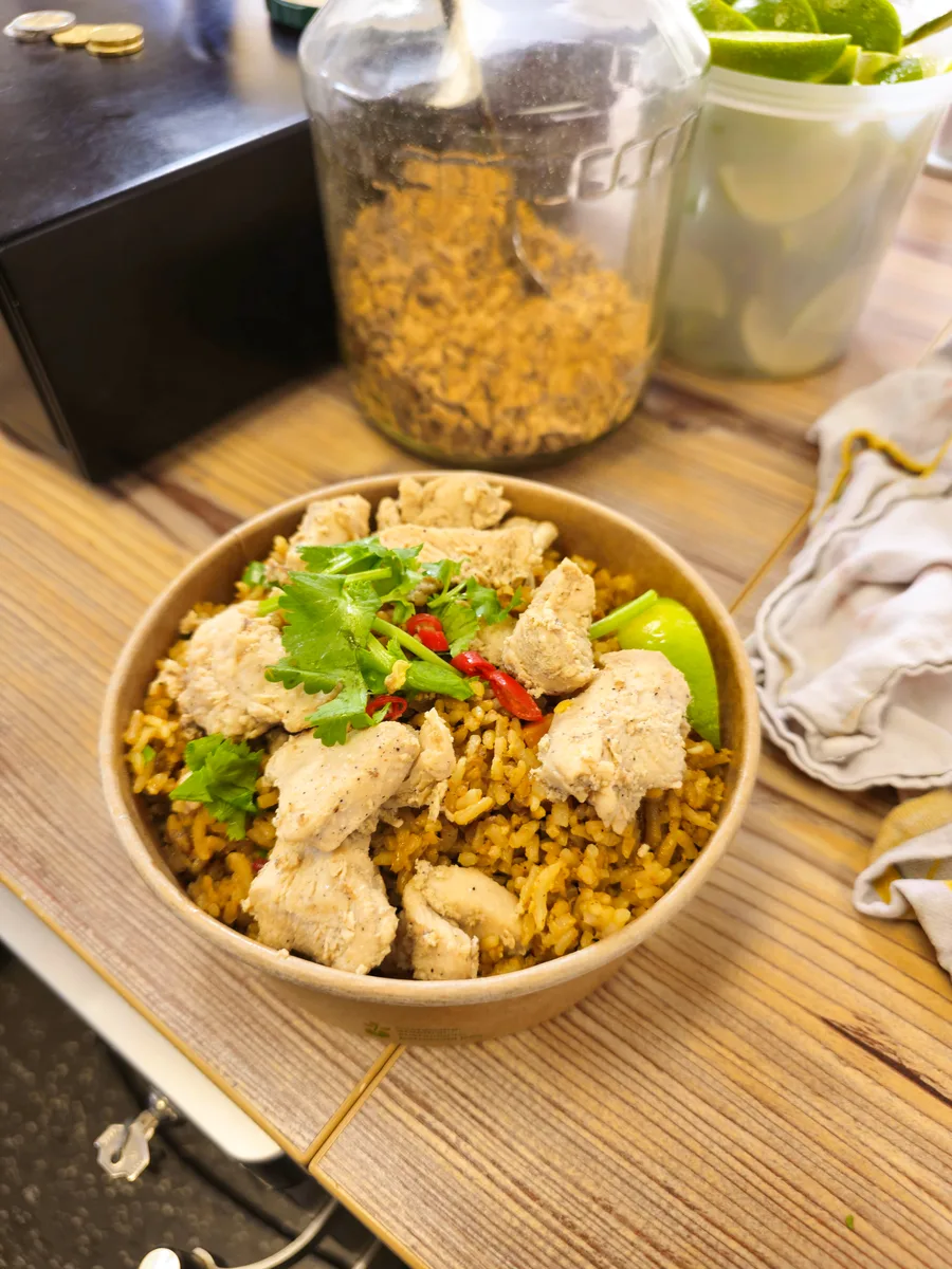 Pineapple Fried Rice mit Hähnchen, Koriander und Chili in einer Takeaway-Schale