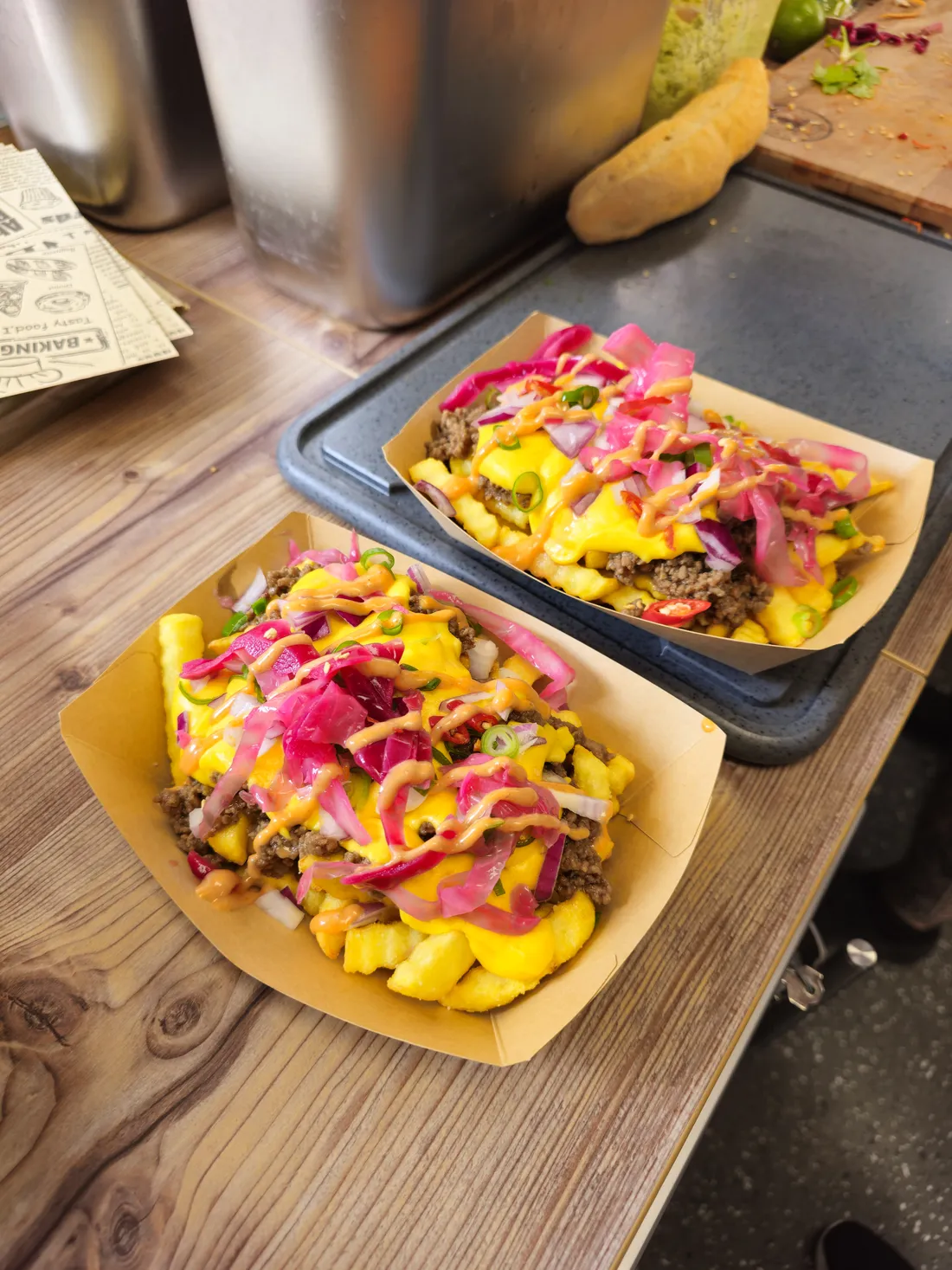 Zwei Portionen Loaded Fries mit Käsesauce, Hackfleisch und pink eingelegtem Rotkraut