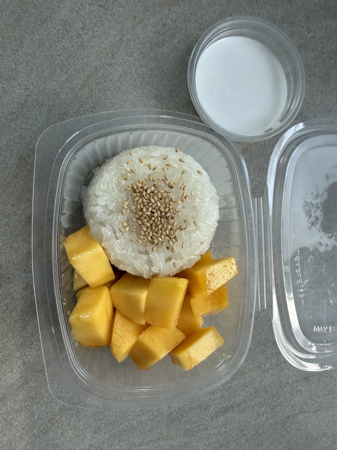 Mango Sticky Rice mit Sesam und Kokossauce in einer Takeaway-Box